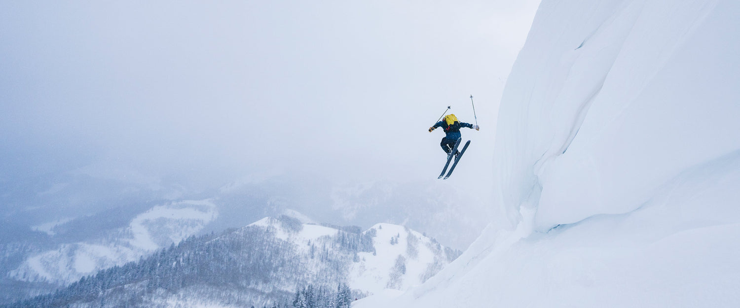 A skier sends it off a snowy cliff in the wasatch.