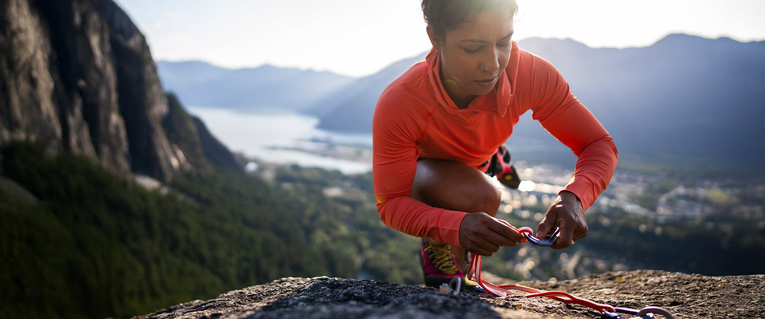 A climber clipping a carabiner on a cliff