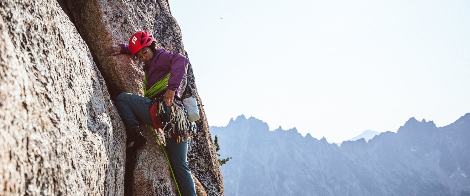 A climber reaches to grab a camalot from her harness