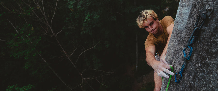 A climber reaches around an arete to clip a quickdraw