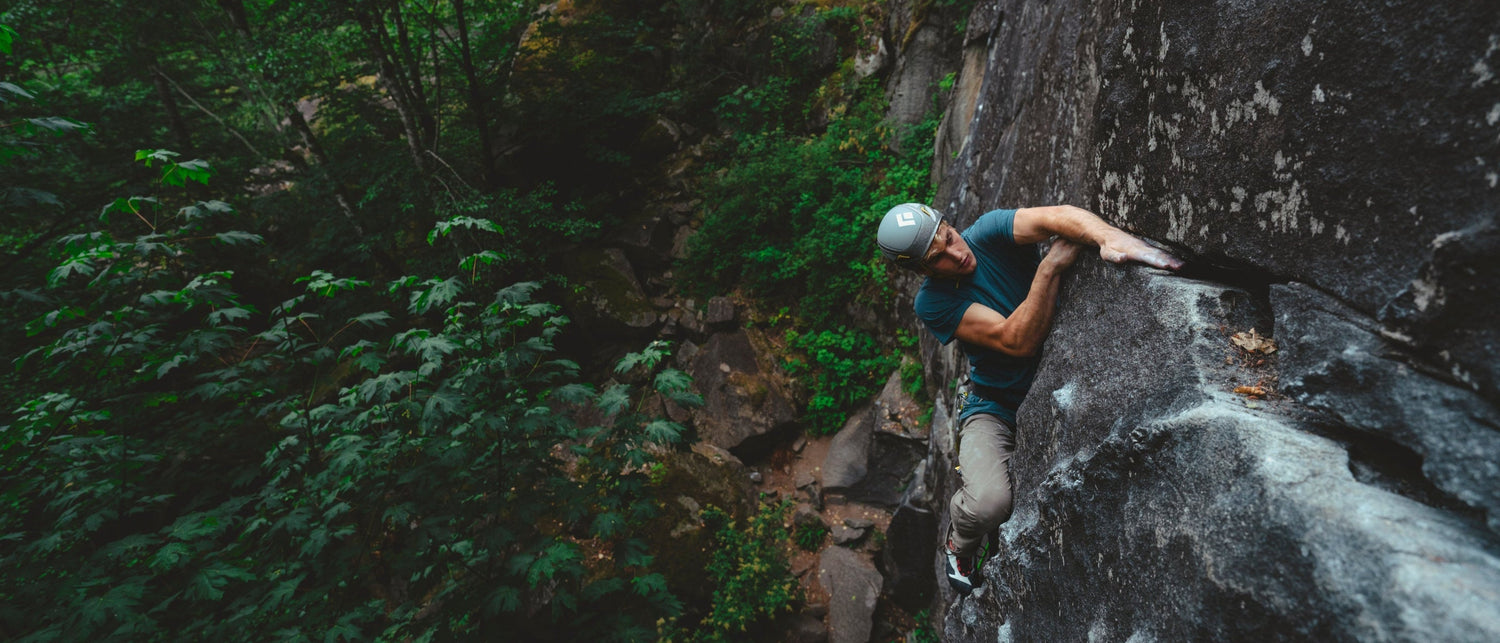 A climber does a knee scrub while reaching for a hold.