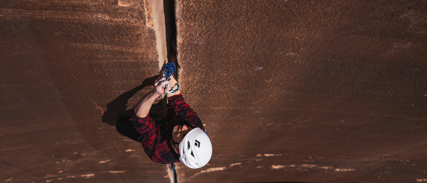 BD athlete Connor Herson places a cam on a crack climb in the desert.