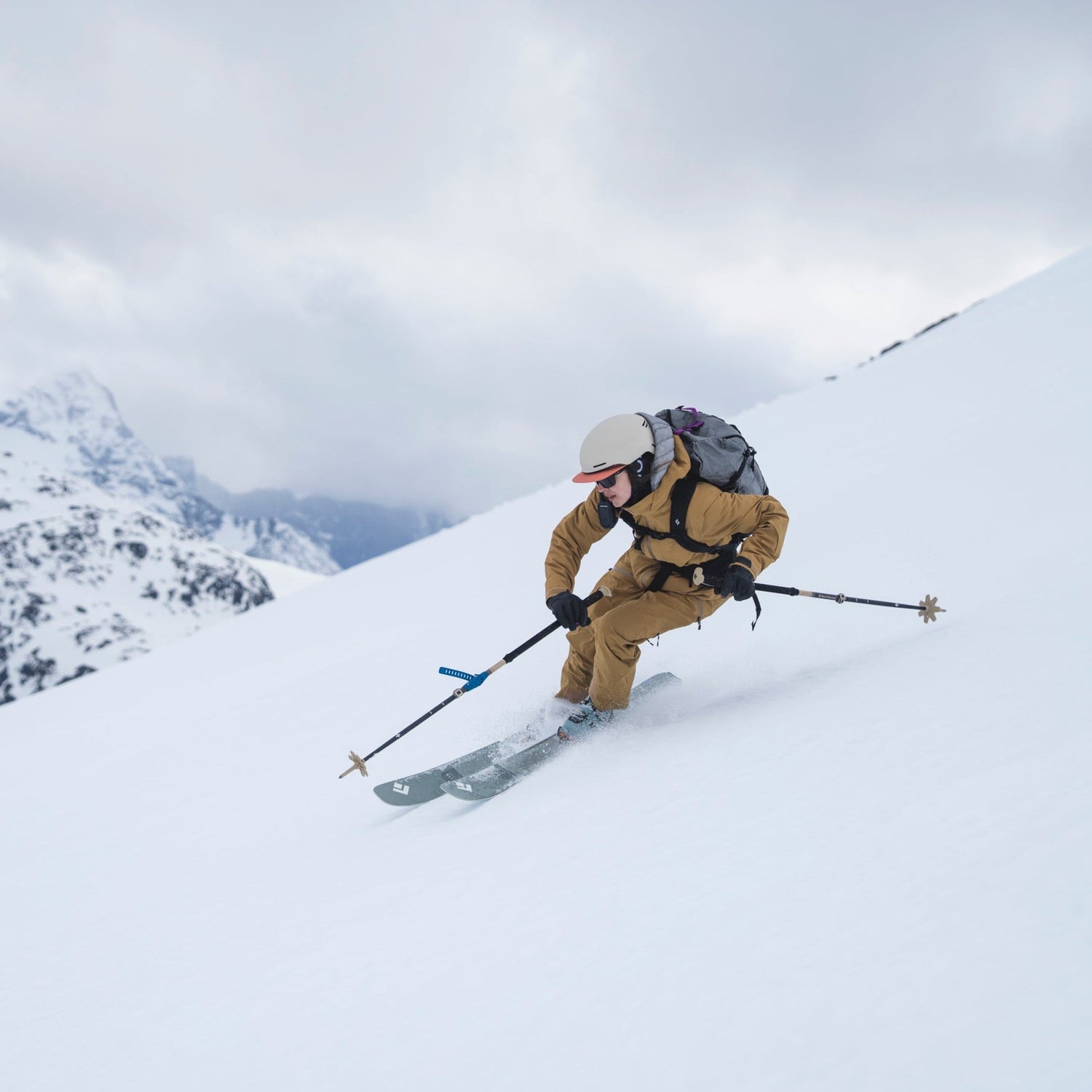 Person skiing down a snowy mountain with backpack and skis