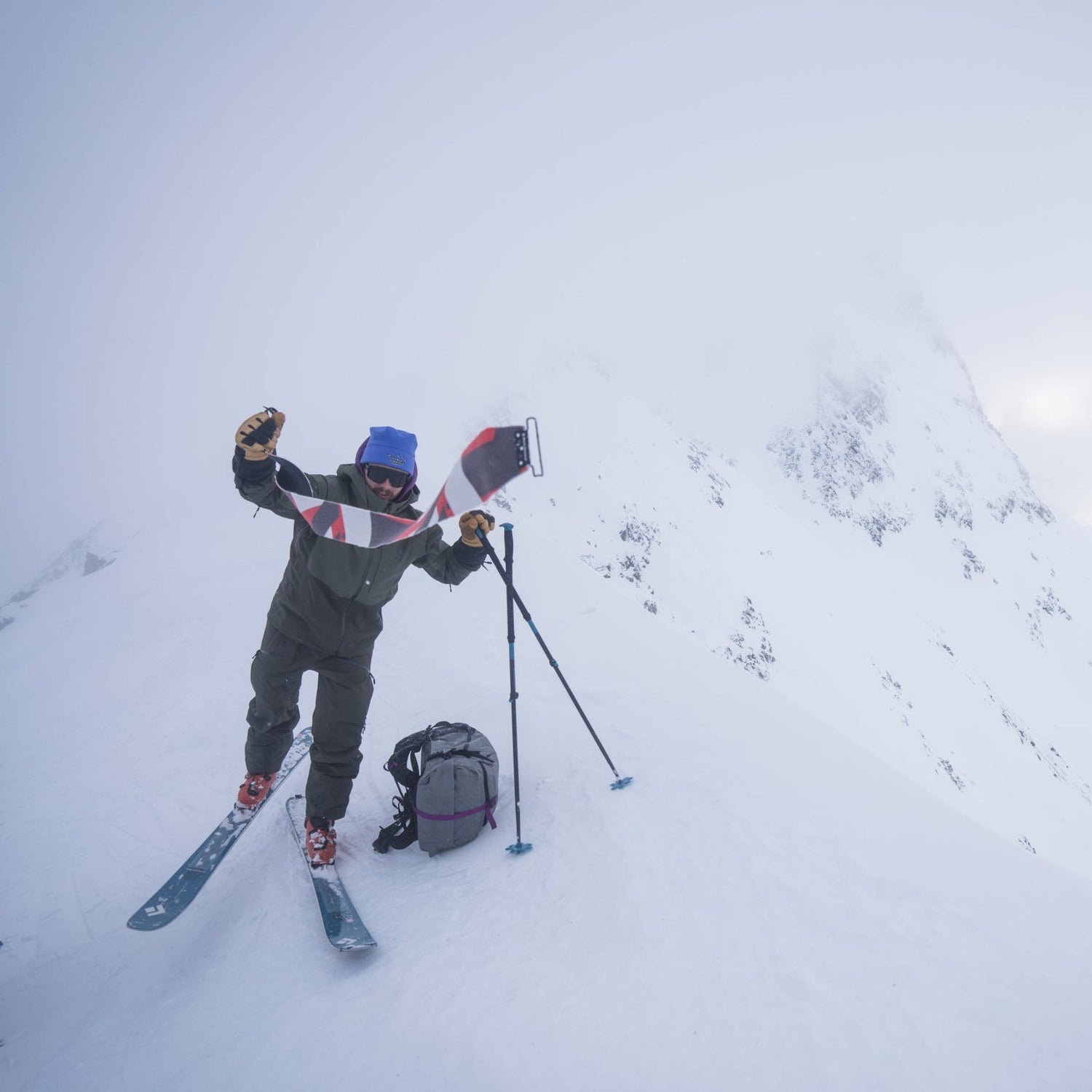 A skier rips the skins on their skis on a foggy ridge.