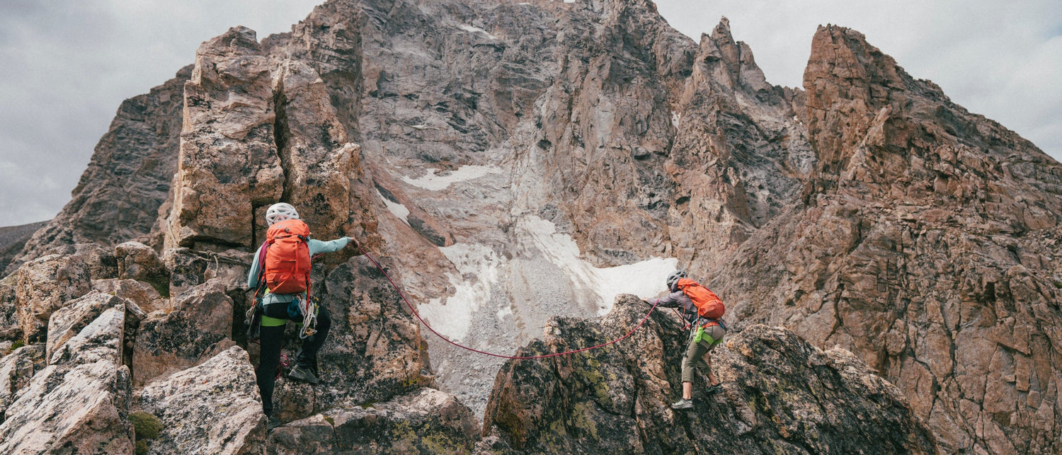 Two climbers in the Tetons with a cloudy sky.