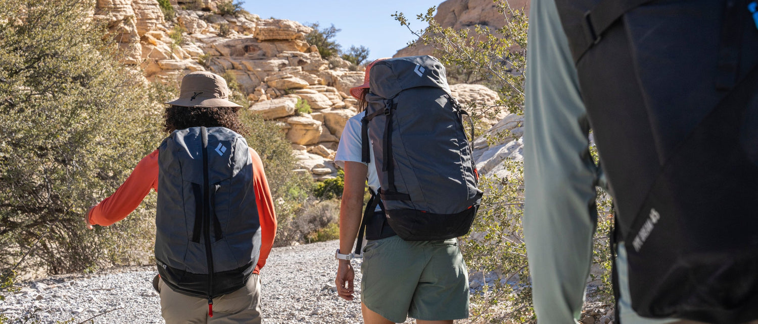 Three climbers wearing Black Diamond backpacks head to a crag in the desert.